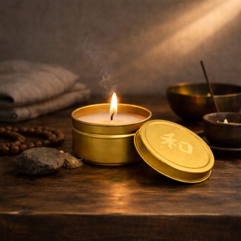 Lit Dragon’s Whisper mini-tin candle in a gold metal tin, shown in a calm, meditative indoor setting.”