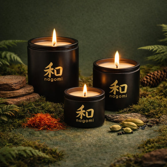 3 Lit Nagomi Sacred Balance candles in black glass jars with saffron, cardamom seeds, and sandalwood in a forest setting
