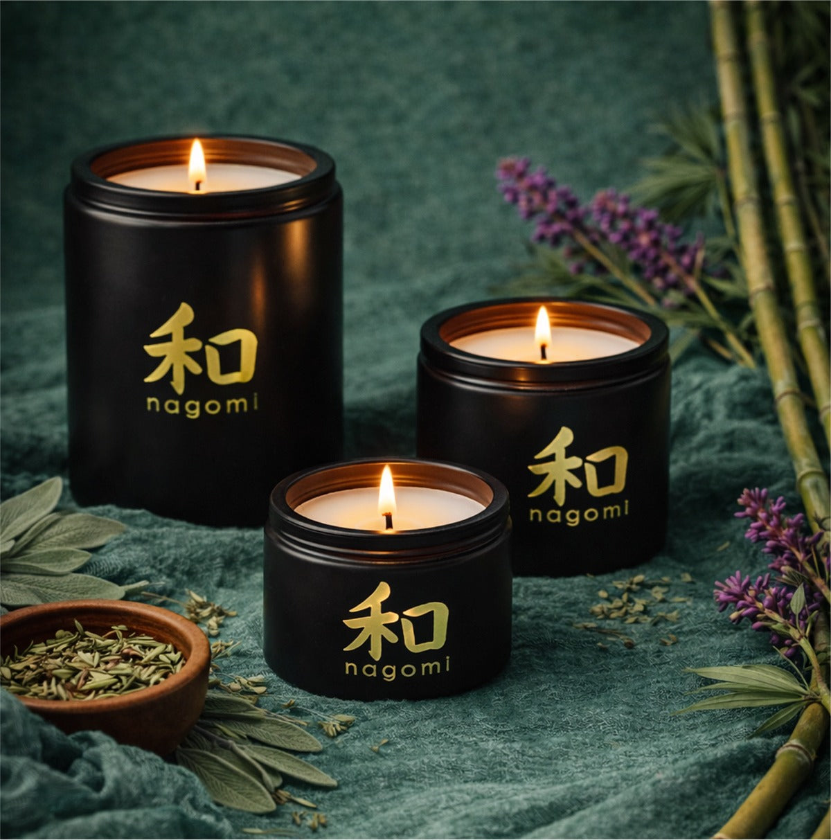 Lit Nagomi Woodland Dream candles in black glass jars on with casaba melon, bamboo, and dark violet flowers