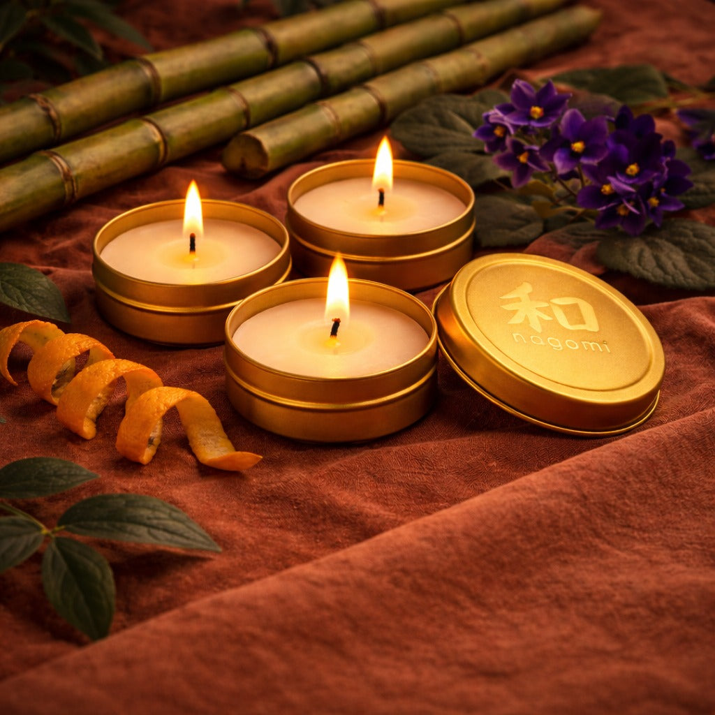 Nagomi Bamboo Breeze mini tin candles in a gold tins with orange peels, bamboo stalks and African violets