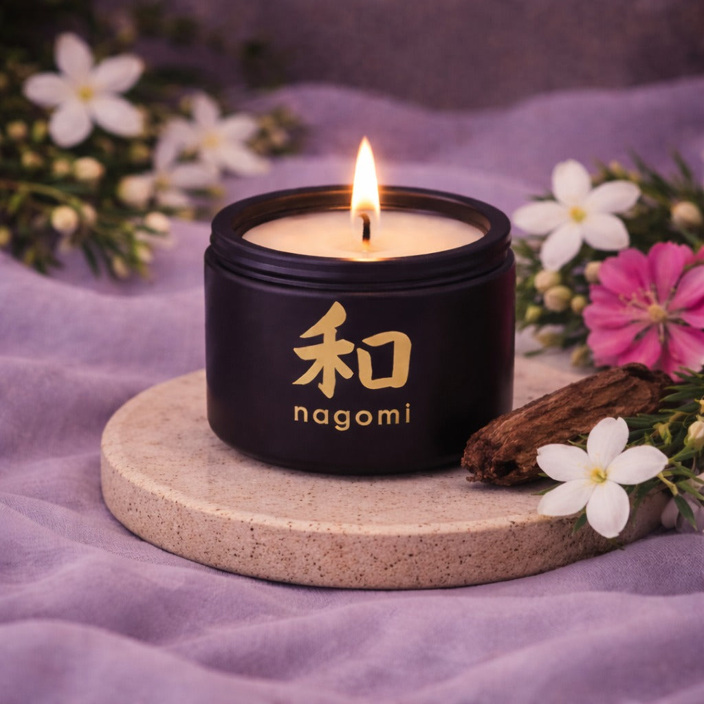 Nagomi Mystic Alchemy 4 oz candle in a black jar with Jasmine, geranium and teakwood in the background